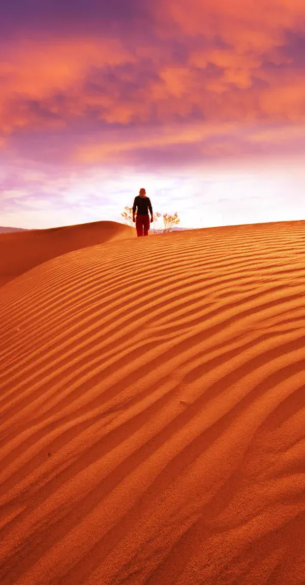 A distant man walking in the desert at sunset